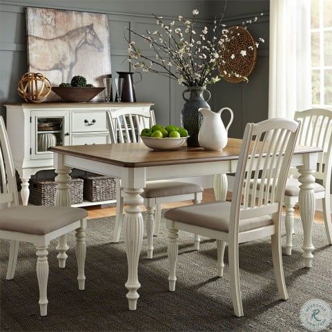 a dining room table with chairs and a bowl of fruit on top of the table