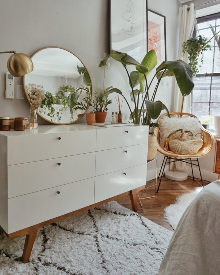 a bedroom with white furniture and plants on the dresser