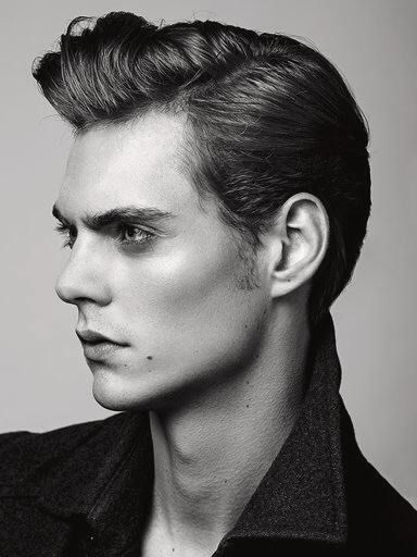 a young man is posing for a black and white photo with his hair pulled back