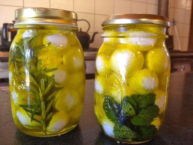 two mason jars filled with lemons and herbs