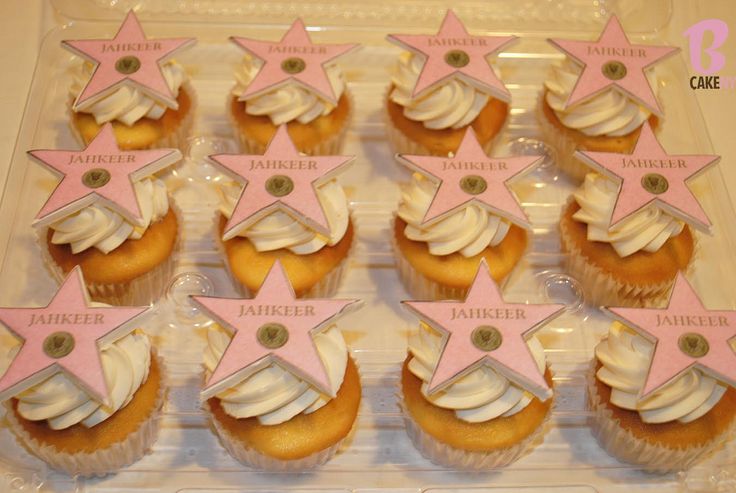 cupcakes decorated with pink and white icing are in a plastic container on a table