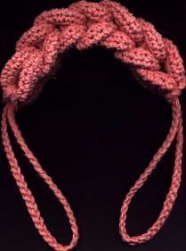 a close up of a pink rope on a black background with an orange object in the foreground