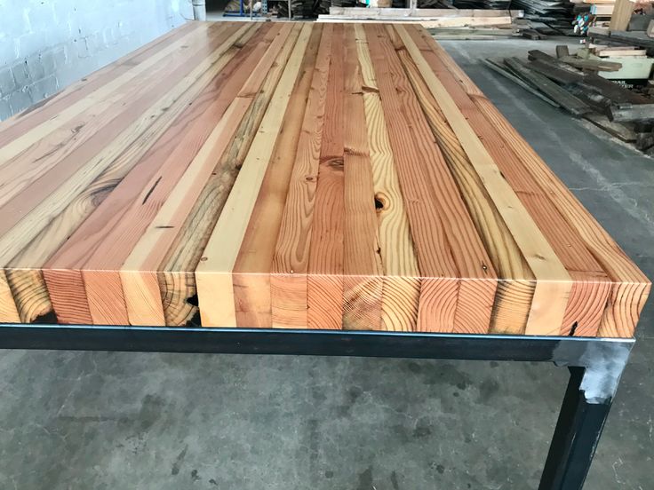 a large wooden table with metal legs in a warehouse or workshop area, ready to be used as a workbench