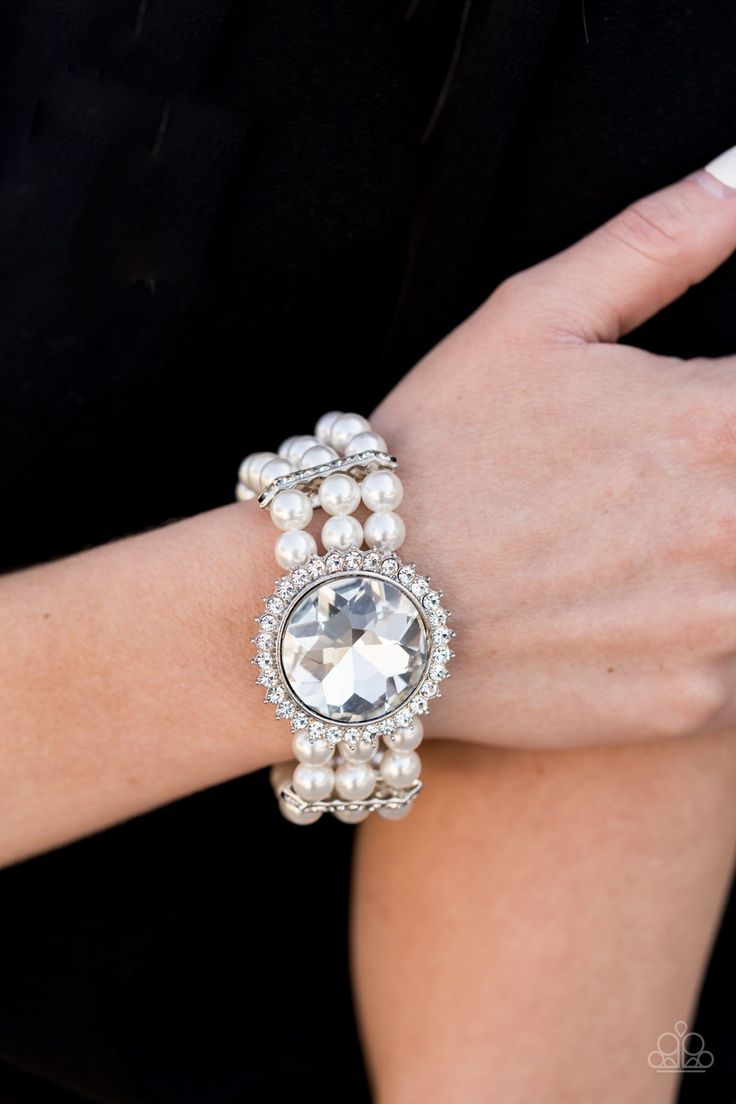 SPEECHLESS SPARKLE - WHITE Threaded along stretchy bands, strands of pearly white beads are held in place with white rhinestone encrusted fittings around the wrist. Bedazzled in a ring of glassy white rhinestones, a dramatically oversized white gem adorns the center for a speechless finish. Sold as one individual bracelet. P9ST-WTXX-013XX ORDERED 29 JUL 20 CONVENTION EXCLUSIVE 2020 Paparazzi Jewelry Images, White Pearl Bracelet, Sparkle Bracelet, Black Gems, White Bracelets, Elegant Bracelet, Paparazzi Accessories, White Rhinestone, Stretchy Bracelets