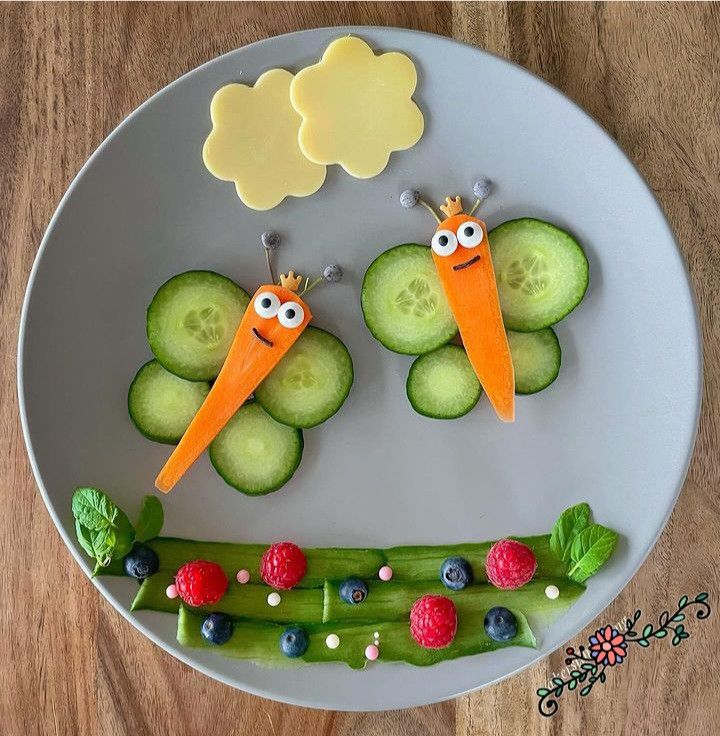 two carrots with faces made out of cucumbers and berries on a plate