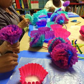 some people are sitting at a table and making cupcakes out of tissue paper