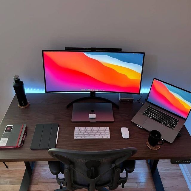 a computer desk with two monitors and a laptop