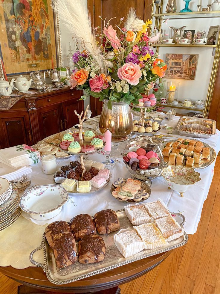 a table full of desserts and pastries on it's side, with flowers in the background