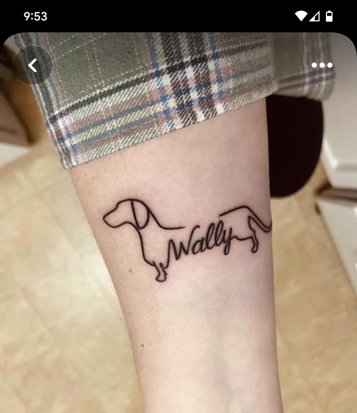 a small dog tattoo on the wrist that says wallflower in cursive font