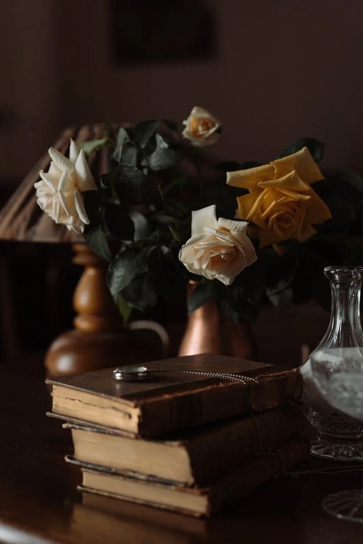 two vases with flowers and books on a table