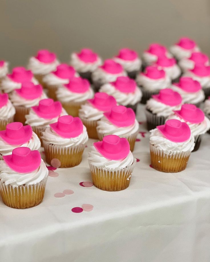 many cupcakes with pink frosting on a table