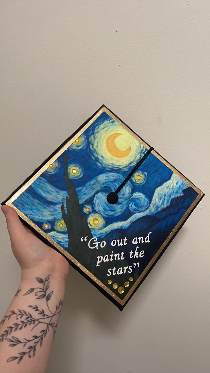 a hand holding up a graduation cap with the words go out and paint the stars