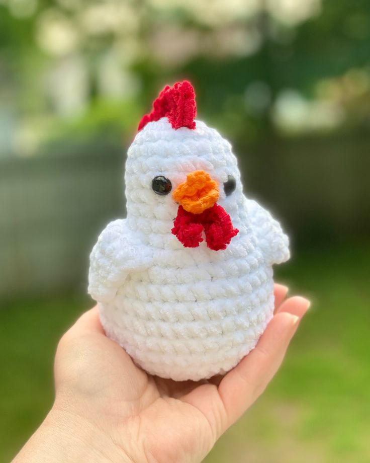 a hand holding a small crocheted chicken