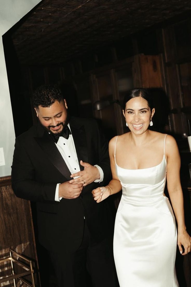 a man in a tuxedo standing next to a woman in a white dress