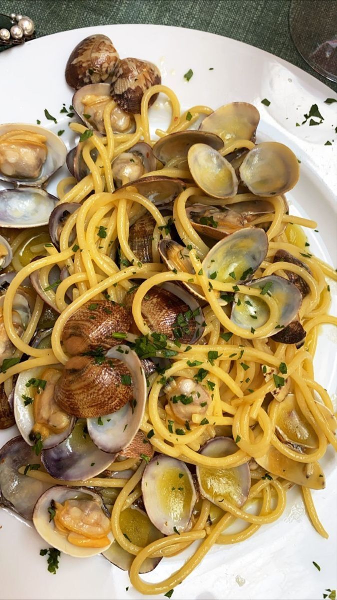 a white plate topped with pasta and clams