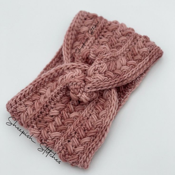 a close up of a knitted headband on a white surface