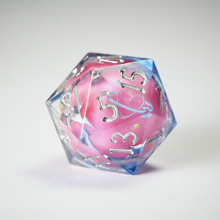 a pink and blue dice sitting on top of a white table