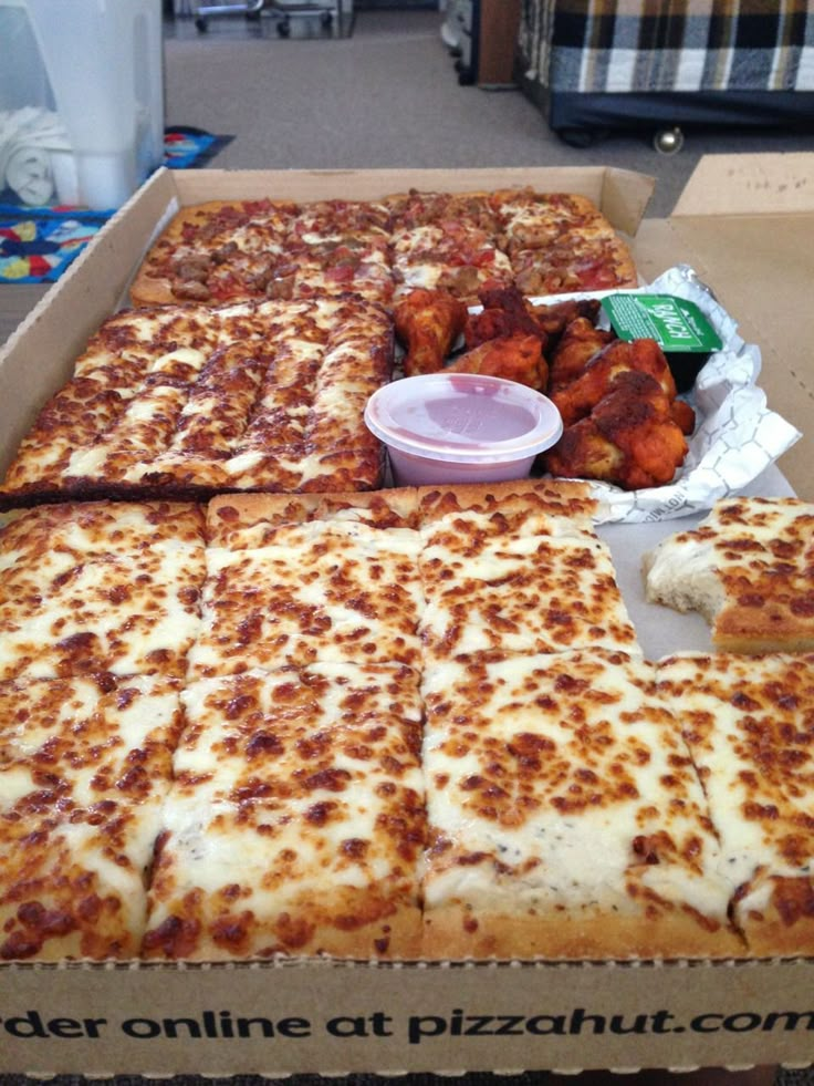 there are several pizzas in the box and one has chicken wings on it as well