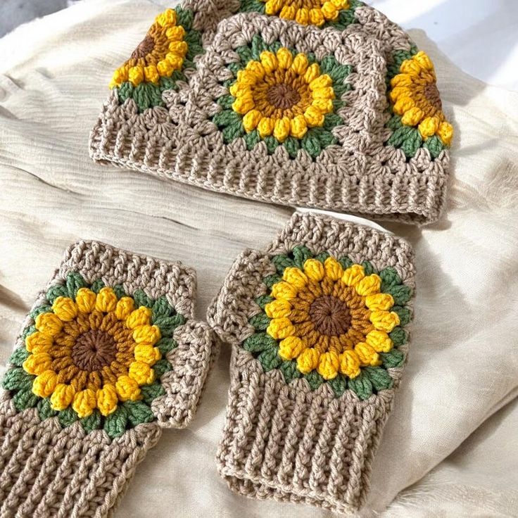 three crocheted sunflower hats and mitts on a bed