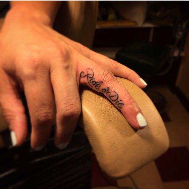 a woman's hand with a small tattoo on her left thumb and the word love written in cursive font