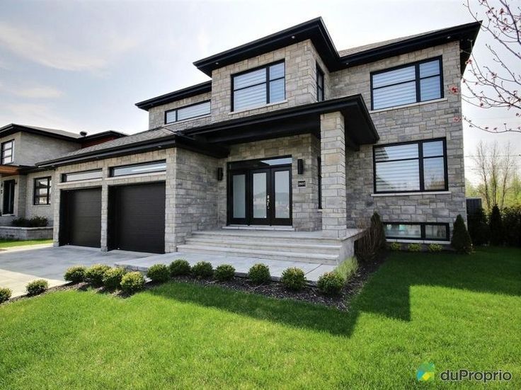 a house that is in the grass with two garages on each side of it