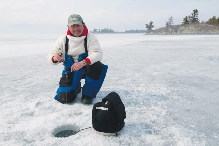 a man kneeling down in the snow next to a backpack