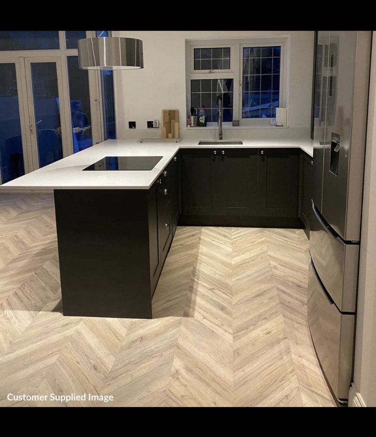 an empty kitchen with wood flooring and stainless steel appliances in the center island area