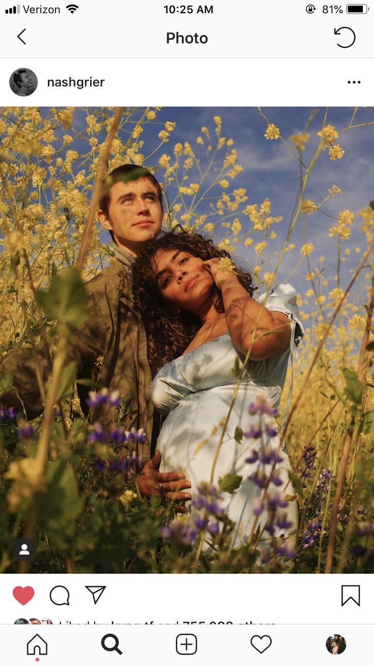 a man and woman are standing in the middle of a field with wildflowers