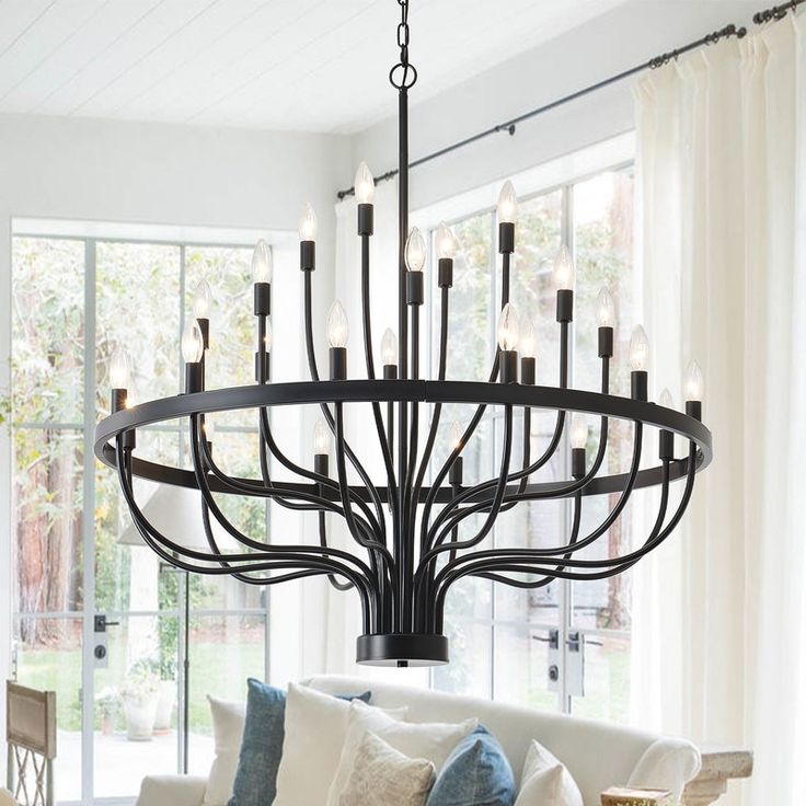 a chandelier hanging from the ceiling in a living room with couches and pillows