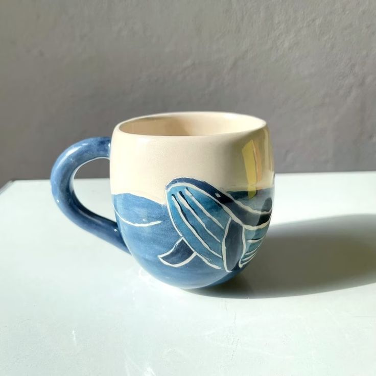 a blue and white coffee cup sitting on top of a table next to a wall