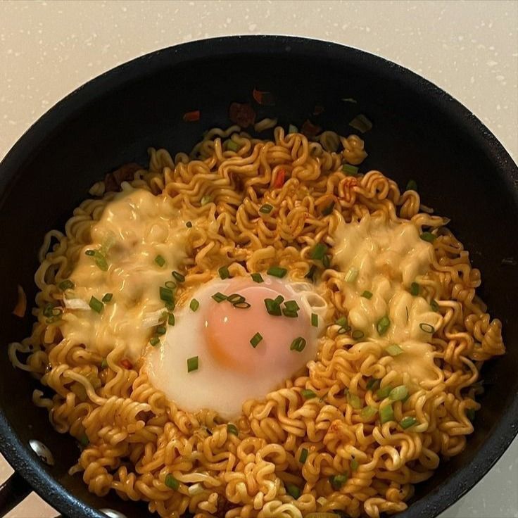 noodles and an egg are being cooked in a skillet