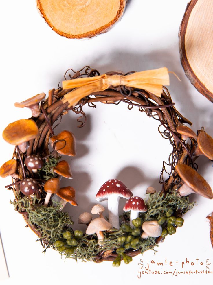 a wreath with mushrooms, moss and other things around it on a white table top