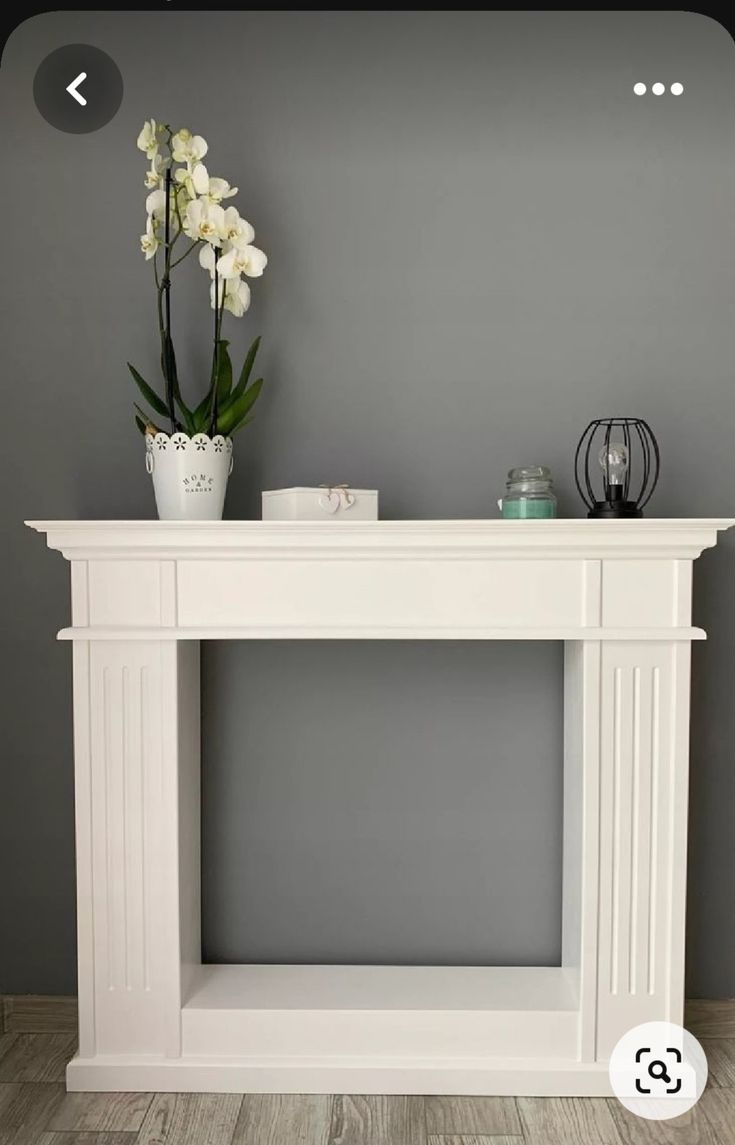 a white fireplace mantel with flowers on top