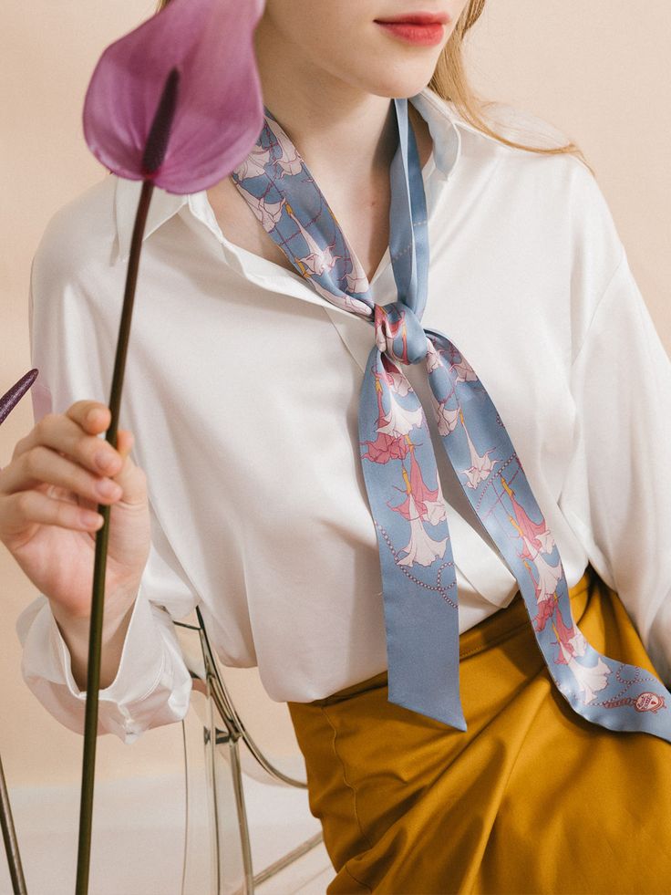 Elevate your wardrobe with the captivating beauty of our "Datura" silk twilly skinny scarf, a stunning accessory inspired by the delicate blooms of the darling darura flower, also known as angel's trumpet. The design embodies the voice of nature, immersing you in its ethereal beauty and transporting you to a realm of tranquility and peace. Made from premium quality silk satin, this skinny scarf is perfect for a hair scarf style. It can also drape elegantly around your neck, immersing you in its Elegant Blue Silk Scarf For Spring, Blue Trendy Silk Scarf For Spring, Chic Blue Silk Scarf For Spring, Trendy Spring Neckwear For Gifts, Feminine Silk Scarf As Spring Gift, Feminine Silk Scarf For Spring Gift, Chic Neckwear For Spring Gifting, Feminine Scarves For Spring Gift, Feminine Spring Scarves As Gifts