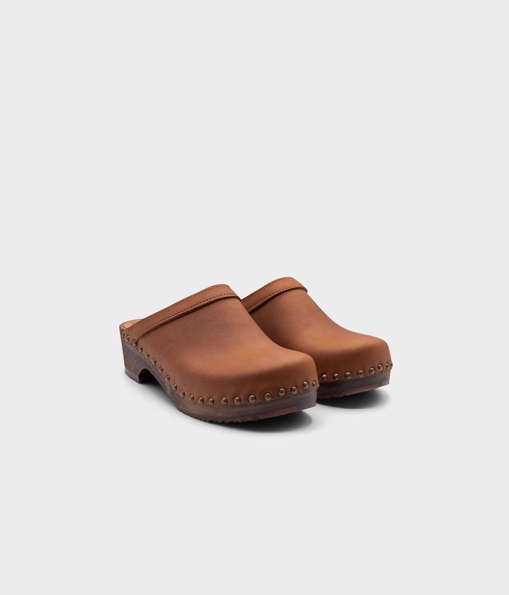 The classic clog mule with an extra touch. Athens wooden clogs in dexter tan, soft nubuck leather is the perfect low-heeled mule for everyday use. The gold studs take these classic clog mules to the next level. All Sandgrens Clogs have been ethically handcrafted with natural materials in Sweden since 1846. Clog measurements:Heel height: 1 3/4 (4.45 cm)Toe height: 1 5/8 (4.1 cm) Fit: RegularLeather:Nubuck leatherClogs consist of:Base: European Lime WoodSole: Rubber soleFastening: Brass studs Classic Leather Closed Toe Clogs, Classic Mules With Wooden Heel, Classic Leather Clogs With Wooden Heel, Classic Mules With Wooden Heel And Round Toe, Rugged Closed Toe Mules With Rubber Sole, Casual Brown Clogs With Studded Rubber Outsoles, Rugged Closed Toe Mules With Leather Sole, Classic Mules With Reinforced Heel And Round Toe, Rugged Closed Toe Mules With Removable Insole