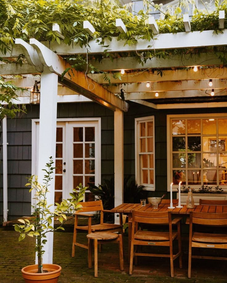 an outdoor dining area with wooden table and chairs, potted plants on the patio