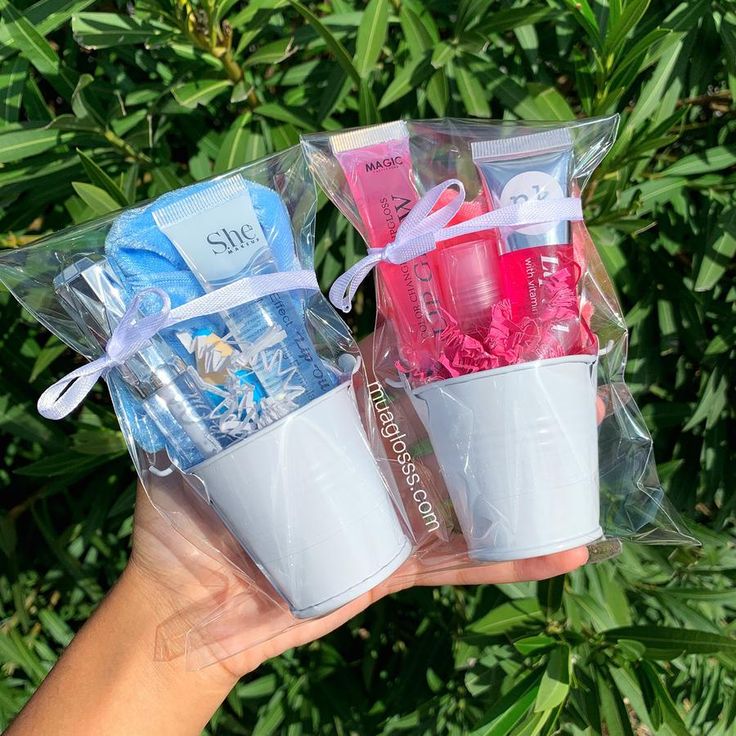 three plastic cups with toothbrushes and soaps in them are held by someone's hand