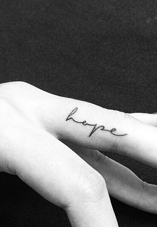 a woman's hand with a small tattoo on it that says love in cursive writing