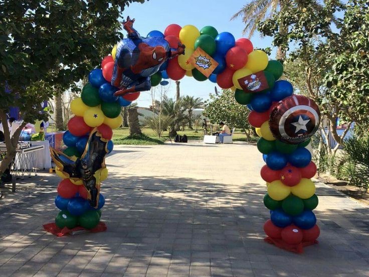 an arch made out of balloons with captain america and iron man on it in the middle of a walkway