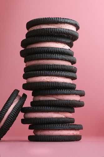 a stack of oreos sitting on top of each other in front of a pink background