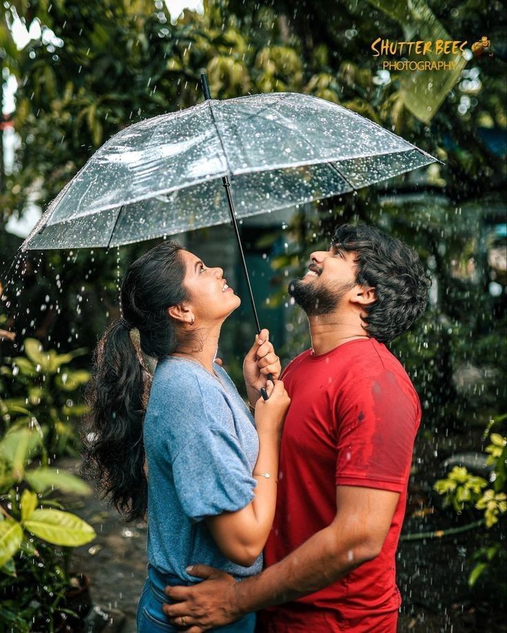 a man and woman standing under an umbrella in the rain with water droplets on them