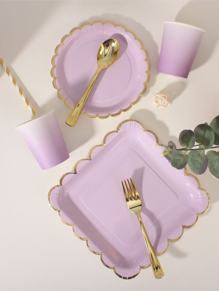 a table setting with pink plates and goldware