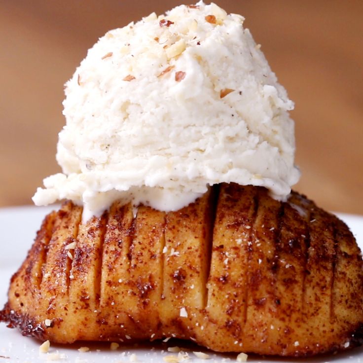 a piece of food with ice cream on top is sitting on a white plate in front of a wooden table