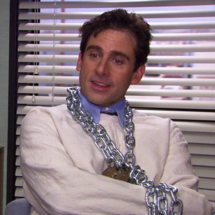 a man in a white shirt and tie with chains on his neck posing for the camera