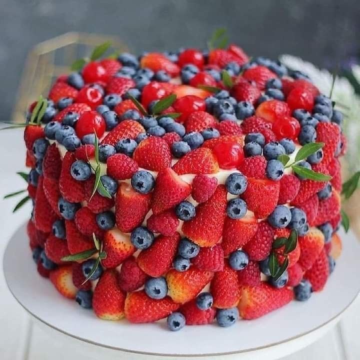 a cake covered in fresh berries and blueberries