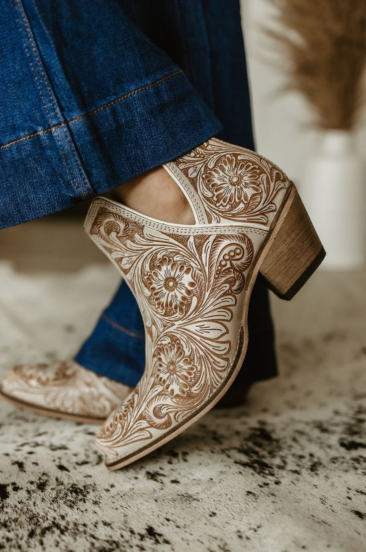 Elevate your style with our Western Moxie Hand-tooled Booties. Hand-crafted from rich white and chocolate-hued leather, these booties feature classic cowboy heels and stylish side slits for easy wear. The intricate hand-tooled design, inspired by desert blossoms, adds a touch of Western sophistication to any outfit. Pl Black Western Shoes, Fashionable Boots Women, Boho Bridal Shoes Comfortable, Winter Womens Dress Shoes, Tooled Leather Boots, Flat Cowboy Boots, Woman’s Cowboy Boots, Cowboy Boots Bridesmaids, Western Booties With Dress