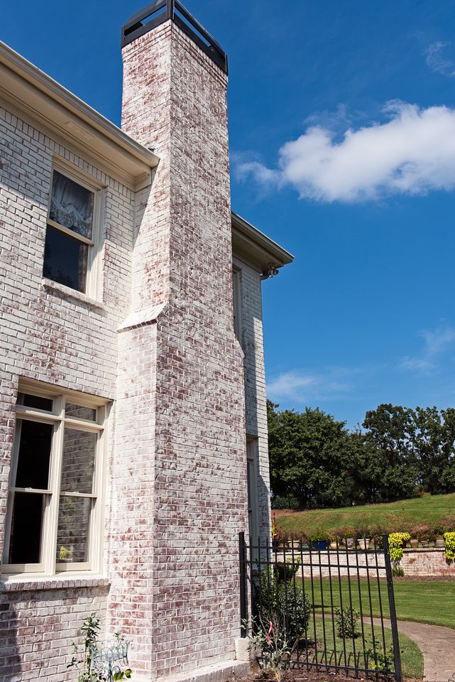 a tall brick tower sitting next to a lush green field on top of a blue sky day