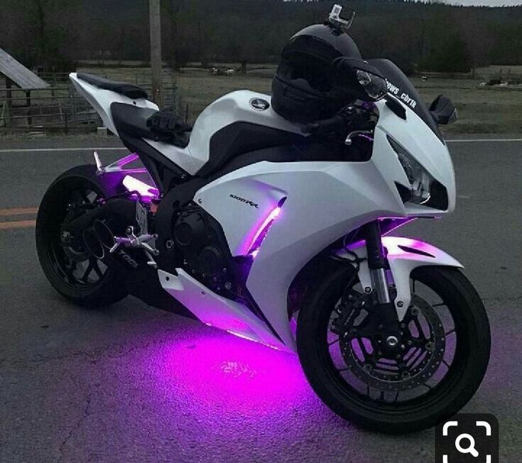 a white and black motorcycle with purple lights on it's front tire rims