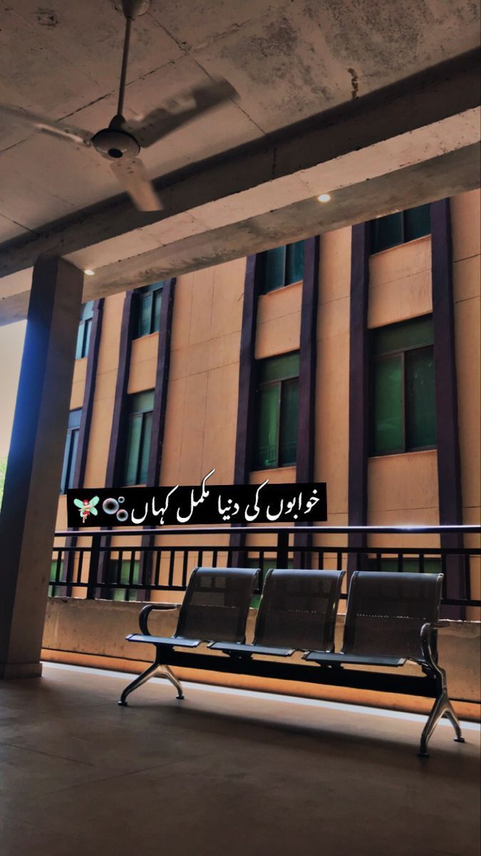 an empty bench sitting in front of a building with arabic writing on the back wall