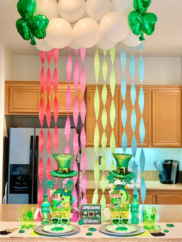 the table is set for st patrick's day with balloons and streamers hanging from the ceiling